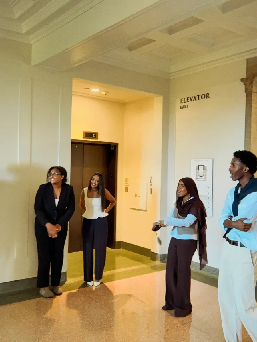 Four people talking and smiling together in a marble elevator lobby