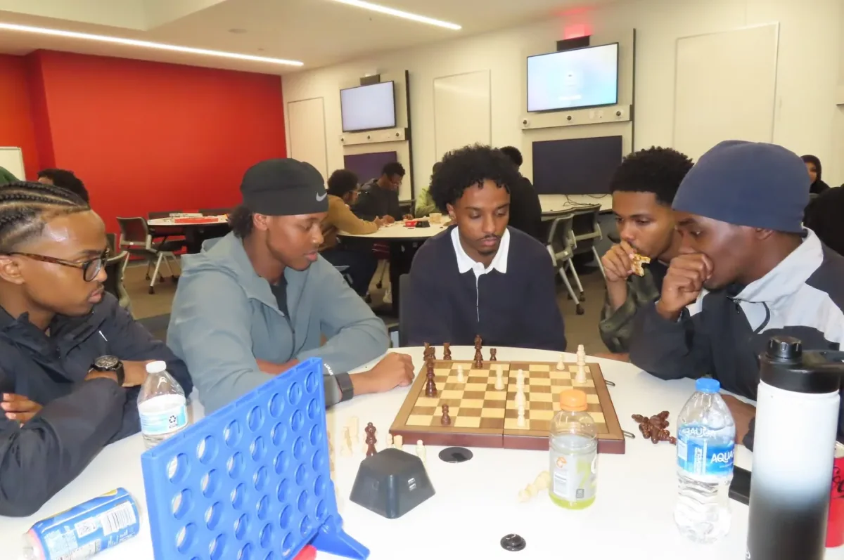 ColorStack UMN members playing chess and Connect Four around a table at game night