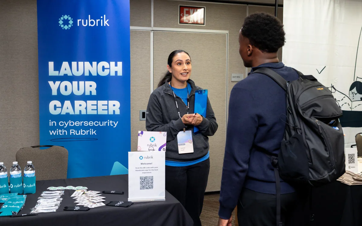 A recruiter talking with a student at a Rubrik recruiting booth at the Stacked Up Summit